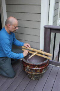 man using plastic zip ties to connect two pieces of bamboo with a third one…